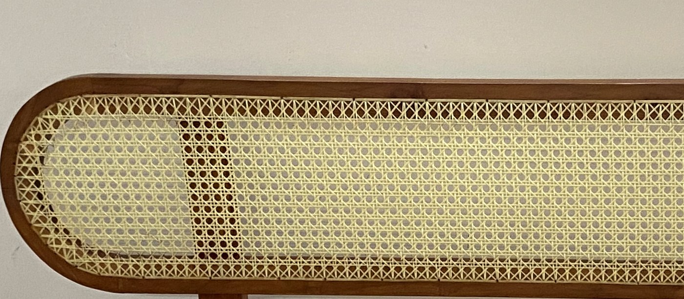 Close-up of the hand-woven cane panel and its rounded teak frame