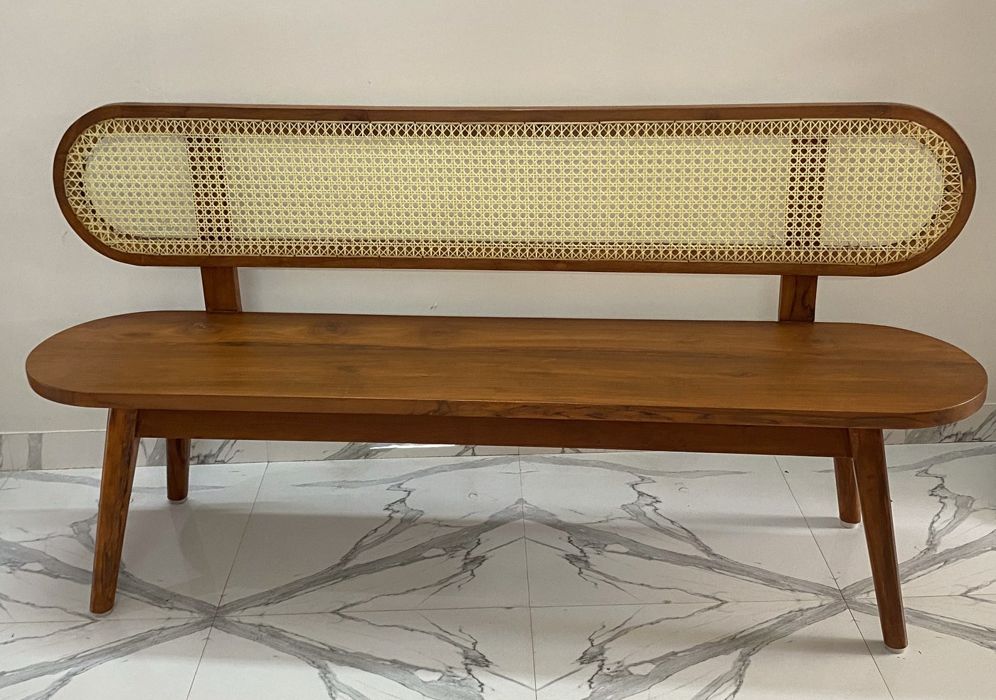 Teak bench with a rounded hand-woven cane back