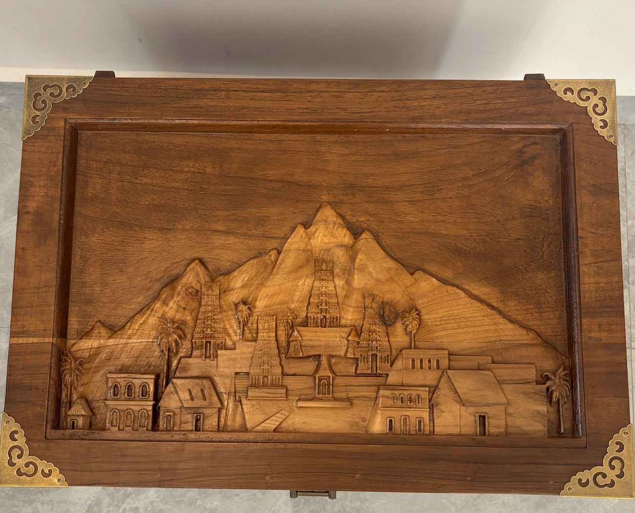 A chest lid carved with a temple-town scene, bound in brass