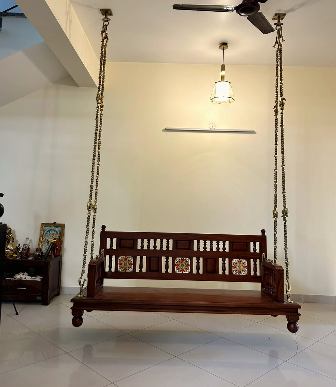 A teak oonjal swing hung in a customer's living room