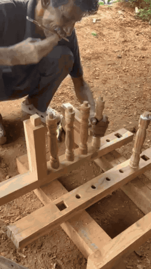 An Annam Woodworks carpenter fitting turned teak spindles into a bench rail